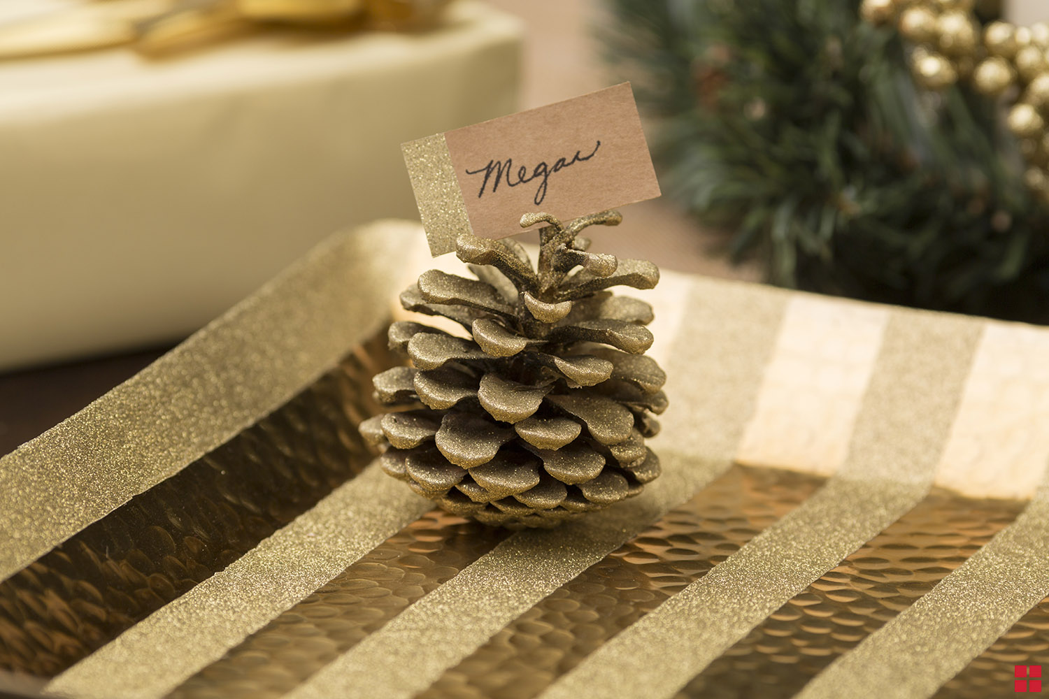 Glittery gold pine cone holding a “Megan” name card.