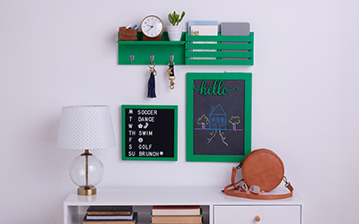 Green shelf, message board and chalkboard on a wall. 