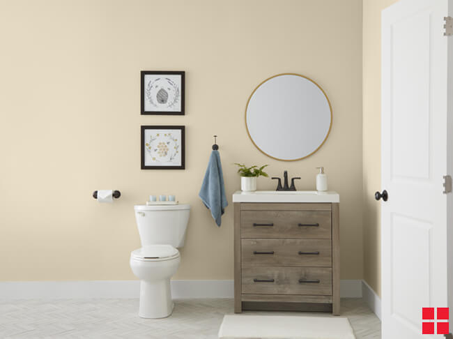 A toilet and sink in a bathroom with walls painted a creamy beige color. 