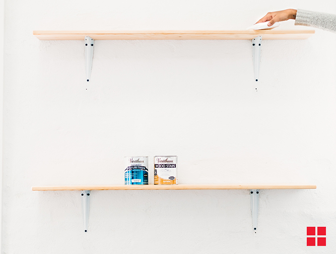 Two bare wood wall shelves with cans of Varathane wood stain on them.