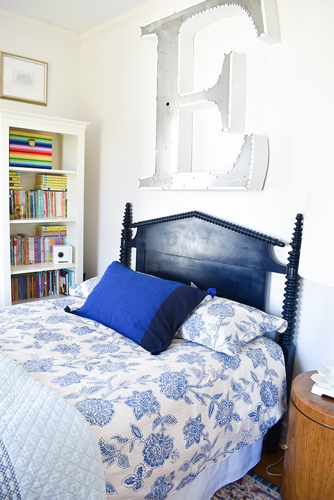 Navy blue headboard behind a bed in a girl’s bedroom.