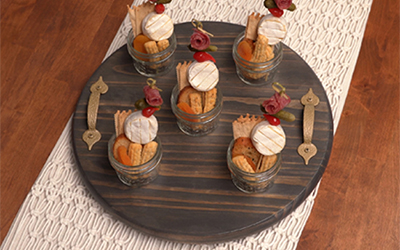 Stained wooden serving tray with charcuterie jars on it.