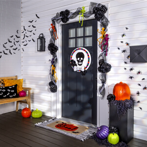 Painted Halloween sign hanging on a door with Halloween garland and painted pumpkins around it.