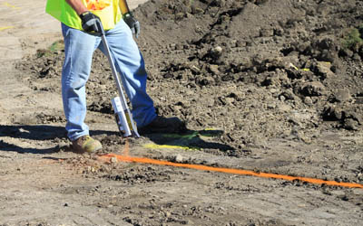 Professional spray painting orange paint onto ground