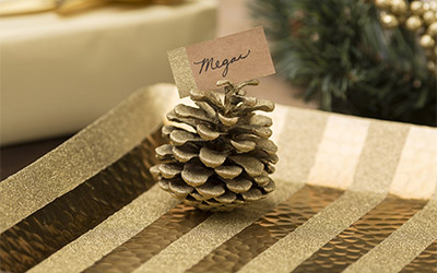 Glittery gold pine cone holding a “Megan” name card.