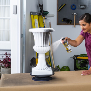 Woman painting a white urn with Rust-Oleum spray paint.